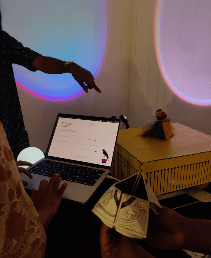 Visitors using the Klimate Kundli laptop beside a printed reading and Dodo the parrot astrologer